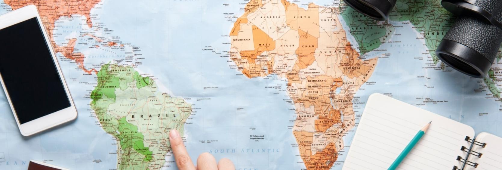 Mappa del mondo con smartphone, binocolo e taccuino.